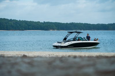 Chaparral 21 SSi on the water near a beach with 2 kids and 2 adults in the boat 