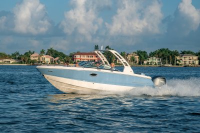 Chaparral 250 OSX cruising in a channel with big houses in the background 