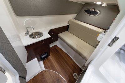 Chaparral 280 OSX head compartment with seating, pull-out toilet, sink, and portlight. 