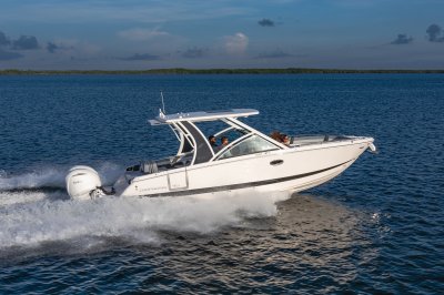 Chaparral 310 OSX starboard profile view cruising with a shoreline in the background. 