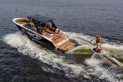 Chaparral 28 SURF with passengers watching a woman surf on a port-side wave. 