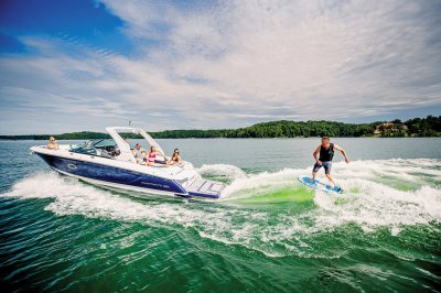Chaparral 30 SURF with a man surfing behind on a port-side wave. 