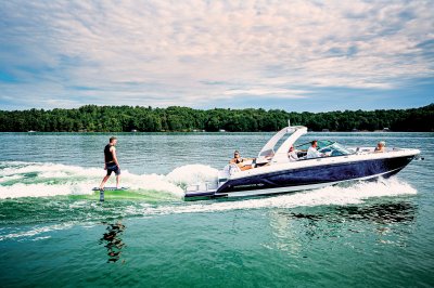 Chaparral 30 SURF with a man surfing behind on a starboard-side wave. 